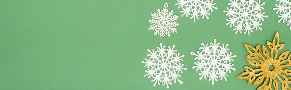 Récolte panoramique de flocons de neige décoratifs blancs et dorés sur fond vert avec espace de copie — Photo de stock