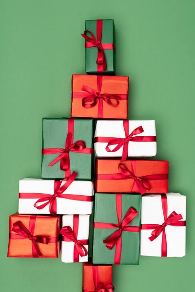 Vue du dessus des boîtes-cadeaux colorées en forme d'arbre de Noël sur fond vert — Photo de stock