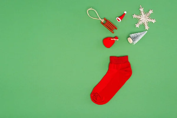 Top view of red christmas stocking near festive baubles on green background with copy space — Stock Photo