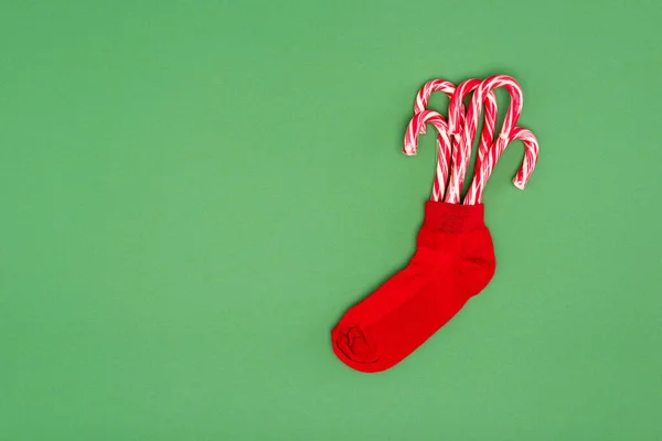 Red christmas stocking with candy canes on green background with copy space — Stock Photo