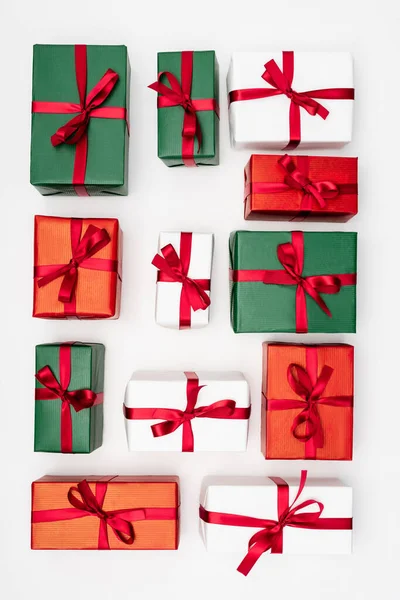 Top view of multicolored gift boxes with red ribbons on white background — Stock Photo