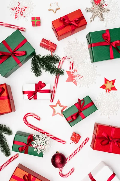 Vista superior de cajas de regalo, bastones de caramelo, galletas en forma de estrella, ramas de abeto y copos de nieve decorativos sobre fondo blanco - foto de stock