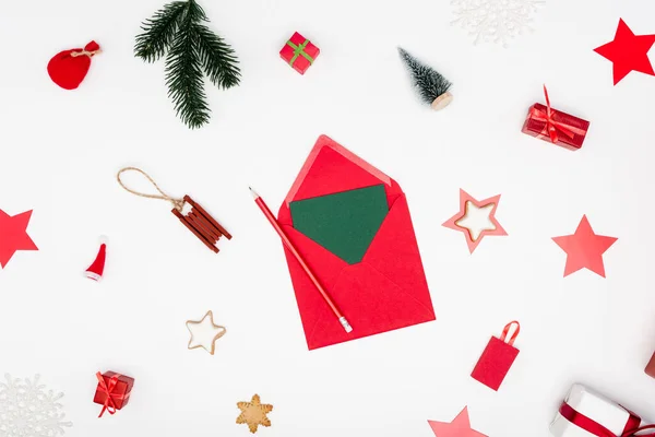 Вид зверху на червоний конверт з картою та олівцем біля різдвяних валіз та запеченими зірками на білому — стокове фото