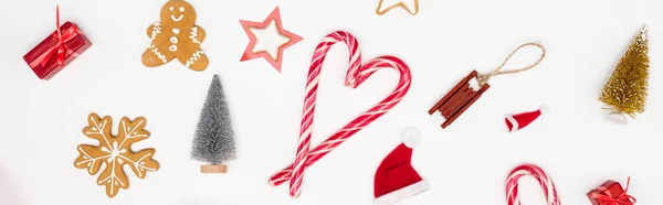 Concepto panorámico de bastones de caramelo y galletas cerca de bolas de Navidad sobre fondo blanco - foto de stock