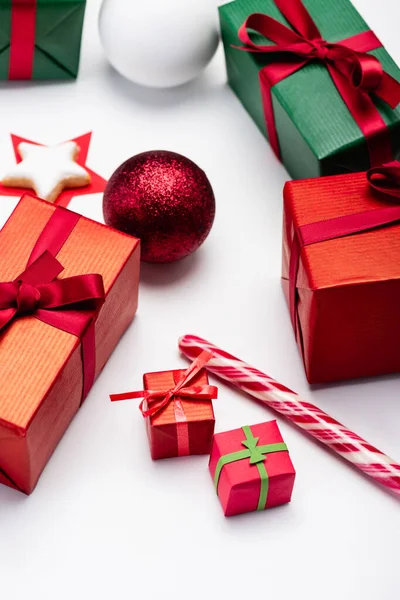 Caixas de presente multicoloridas, bolas de Natal, cana-de-açúcar e biscoito em forma de estrela no fundo branco — Fotografia de Stock