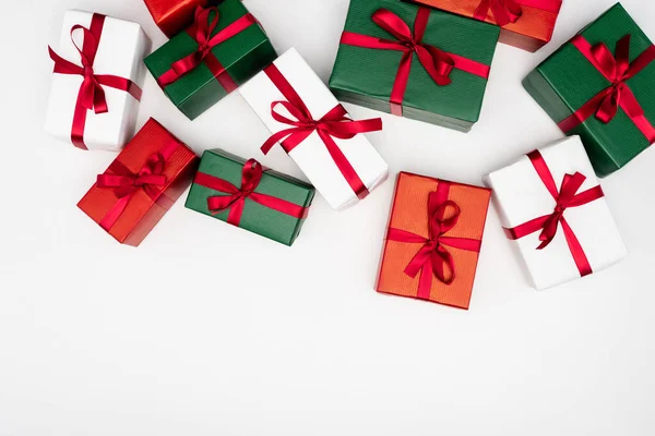 Top view of multicolored gift boxes with red ribbons on white background — Stock Photo