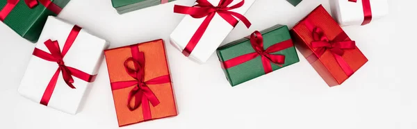 Horizontal concept of colorful gift boxes with red ribbons on white background, top view — Stock Photo