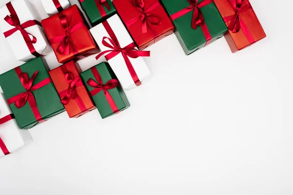 Top view of colorful present boxes with red ribbons and bows on white background — Stock Photo