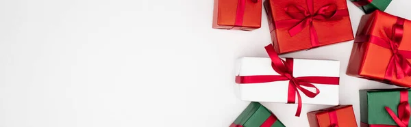 Horizontal concept of colorful gift boxes with red ribbons on white background, top view — Stock Photo