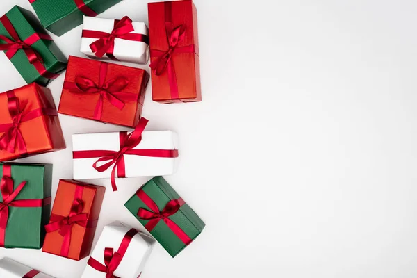 Top view of multicolored gift boxes with red ribbons on white background with copy space — Stock Photo