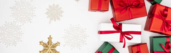 Concept panoramique de boîtes-cadeaux multicolores et de flocons de neige décoratifs sur fond blanc — Photo de stock