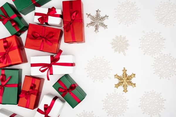 Vue de dessus des boîtes-cadeaux colorées et des flocons de neige décoratifs sur fond blanc — Photo de stock