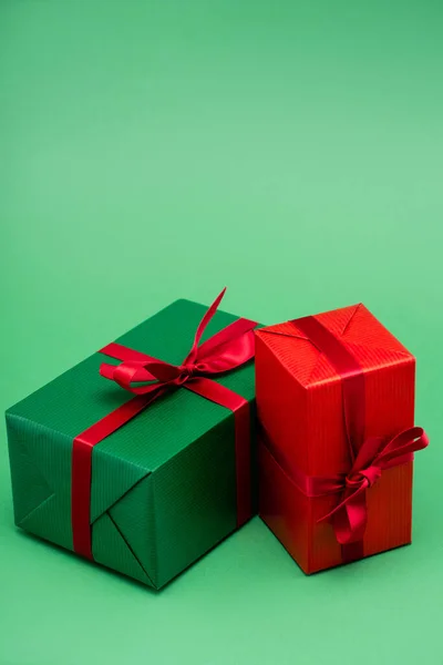 Zwei bunte Geschenkboxen mit roten Bändern und Schleifen auf grünem Hintergrund — Stockfoto