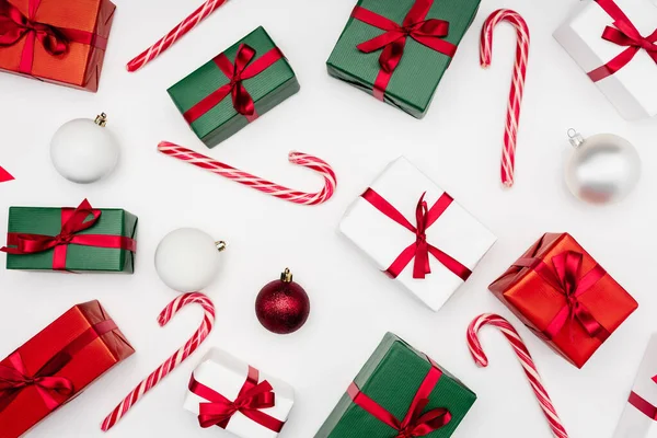 Blick von oben auf bunte Geschenkboxen, Weihnachtskugeln und Zuckerstangen auf weißem Hintergrund — Stockfoto
