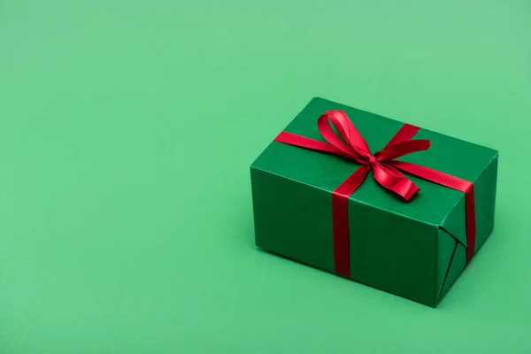 Colorful gift box with red ribbon and bow on green background with copy space — Stock Photo