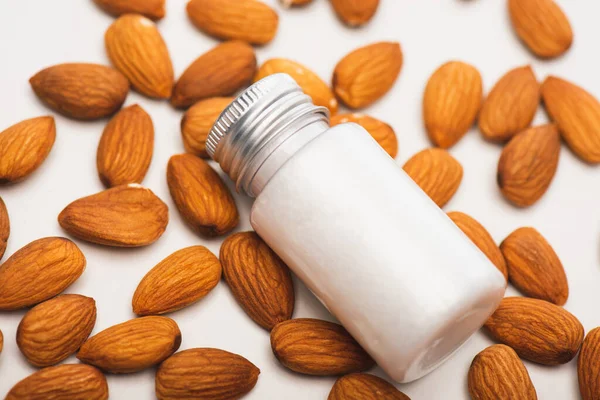 Close up view of bottle with fresh homemade lotion near almonds on white — Stock Photo