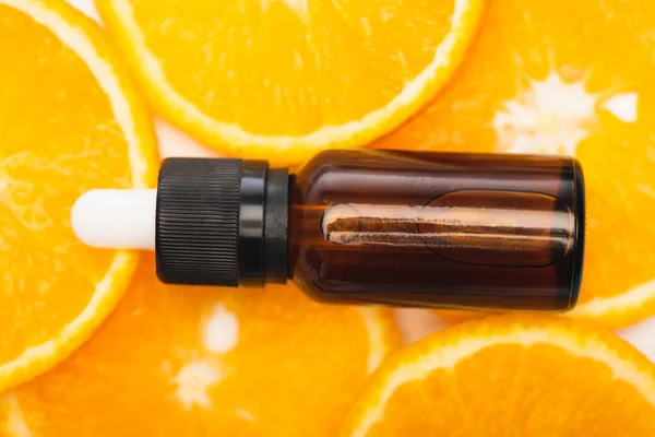 Close up view of bottle with citrus essential oil on juicy, fresh orange slices, top view — Stock Photo