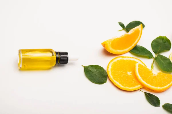 Bottle of fresh homemade citrus essence near juicy orange slices and rose leaves on white — Stock Photo