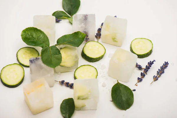 Fresh cucumber slices, rose leaves and lavender flowers on white surface — Stock Photo