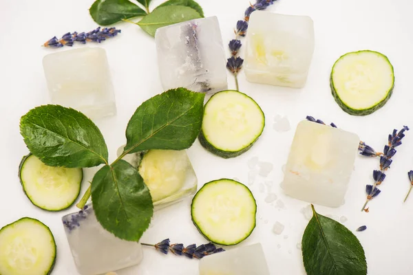 Vue de dessus des cubes de fruits et de fleurs près des tranches de concombre, et des fleurs de lavande sur blanc — Photo de stock