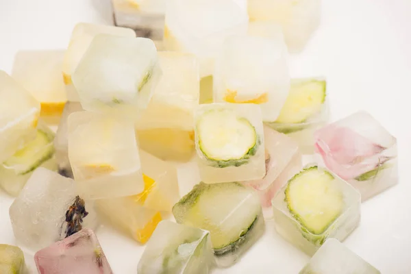 Refrescantes cubitos de hielo florales, vegetales y frutales para el cuidado facial en blanco - foto de stock