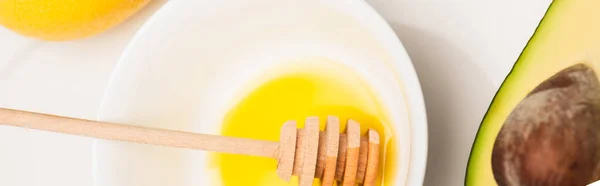 Vista superior del cuenco con miel y cazo de madera, aguacate cortado y limón fresco sobre blanco, pancarta - foto de stock