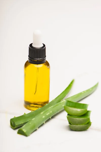 Flasche hausgemachter Aloe Vera Saft in der Nähe von geschnittenen Blättern auf weiß — Stockfoto