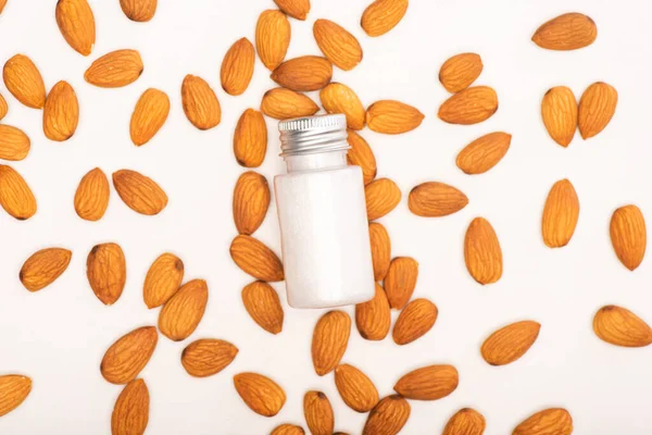 Vue du dessus de la bouteille avec lotion rafraîchissante près des amandes sur la surface blanche — Photo de stock