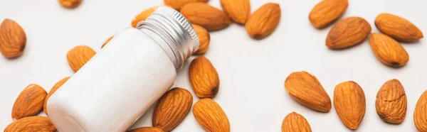 Bouteille avec lotion maison entourée d'amandes sur blanc, bannière — Photo de stock