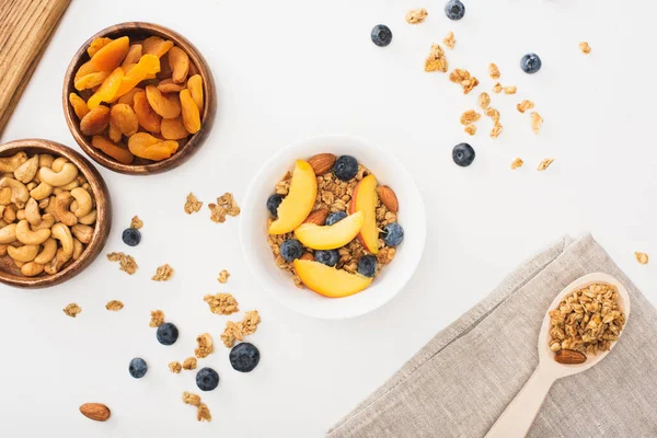 Vista superior de la deliciosa granola con nueces, melocotón, arándanos y albaricoques secos aislados en blanco - foto de stock