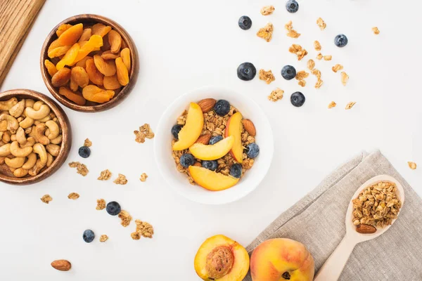 Vue de dessus de délicieux granola aux noix, pêches, bleuets et abricots secs isolés sur blanc — Photo de stock
