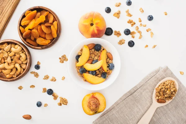 Vue de dessus de délicieux granola aux noix, pêches, bleuets et abricots secs isolés sur blanc — Photo de stock