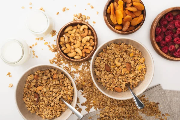 Blick von oben auf köstliches Müsli mit Nüssen, Himbeeren, Joghurt und getrockneten Aprikosen isoliert auf weiß — Stockfoto