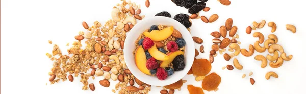 Vue de dessus de délicieux granola avec des noix et des fruits éparpillés dans des bols isolés sur blanc, bannière — Photo de stock