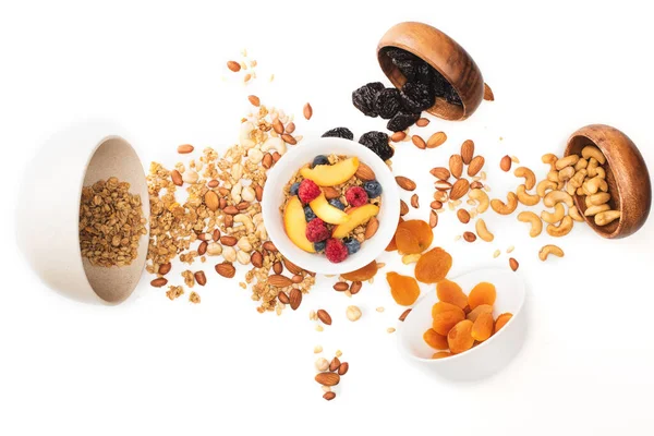 Vista superior de la deliciosa granola con frutos secos y frutas dispersas de cuencos aislados en blanco - foto de stock