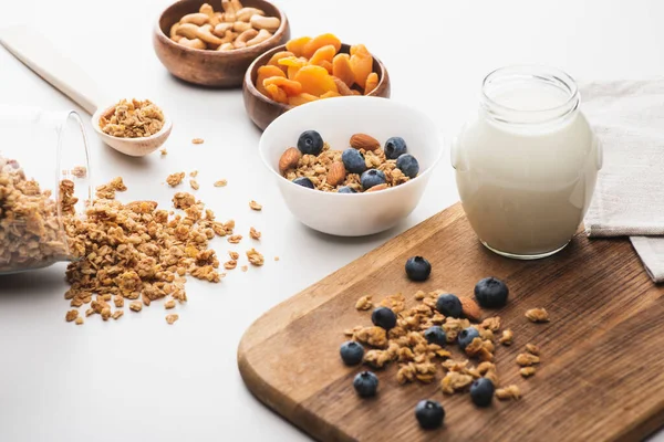 Köstliches Müsli mit Joghurt, Nüssen, getrockneten Aprikosen und Blaubeeren auf weißem Hintergrund — Stockfoto