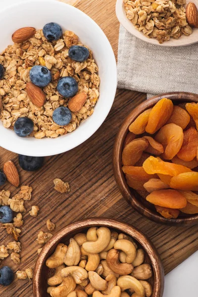 Vue de dessus de délicieux granola aux noix, bleuets et abricots séchés sur planche de bois — Photo de stock