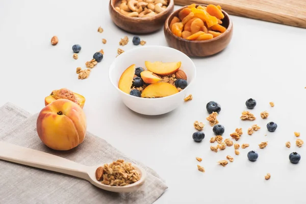 Delicioso granola con nueces, melocotón, arándanos y albaricoques secos en blanco - foto de stock