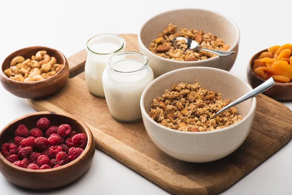 Deliciosa granola com nozes, frutas e iogurte em tábua de madeira sobre fundo branco — Fotografia de Stock