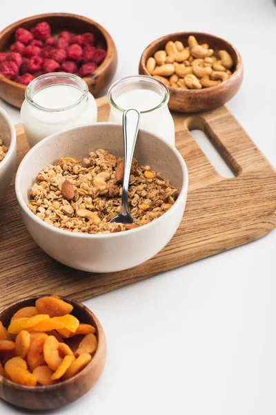 Deliciosa granola com nozes, frutas e iogurte em tábua de madeira sobre fundo branco — Fotografia de Stock