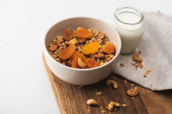 Delicious granola with nuts, dried apricots and yogurt on wooden board on white background — Stock Photo