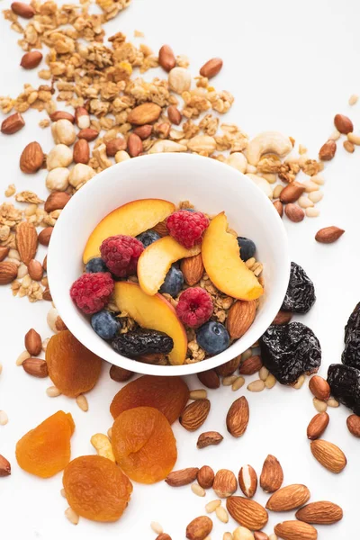 Delicious granola with nuts, berries and fruits in bowl on white — Stock Photo