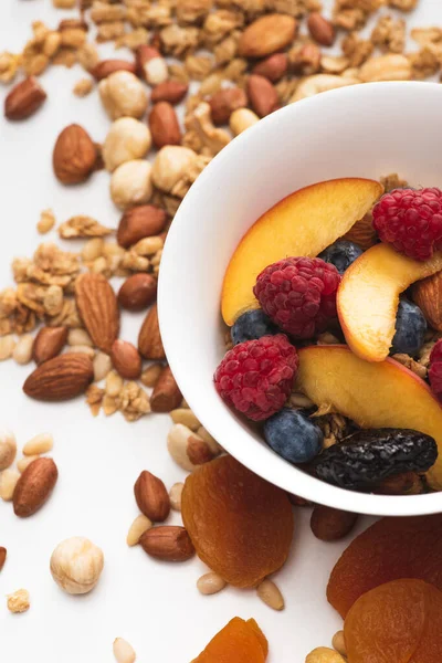 Delicious granola with nuts, berries and fruits in bowl on white — Stock Photo