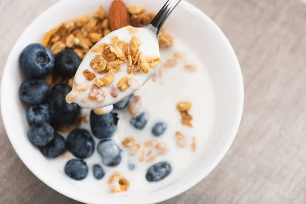 Spoon with delicious granola and yogurt on blurred background — Stock Photo