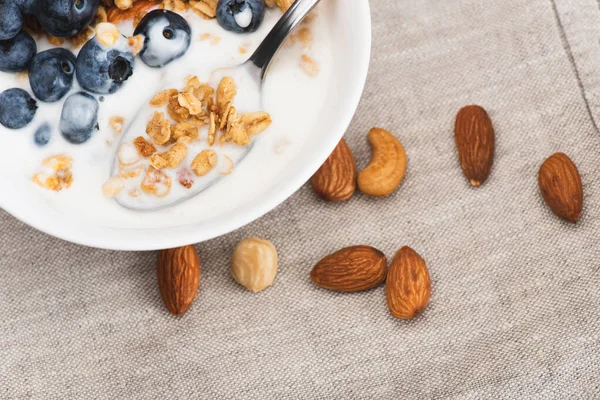 Close-up de granola deliciosa com nozes, iogurte, mirtilo em tigela com colher — Fotografia de Stock