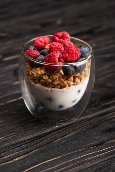 Deliciosa granola com bagas e iogurte em copo de vidro na superfície de madeira — Fotografia de Stock