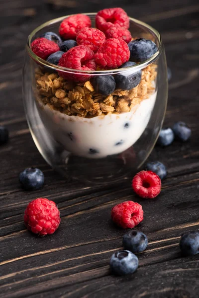 Closeup of delicious granola with berries and yogurt in glass cup on wooden surface — Stock Photo