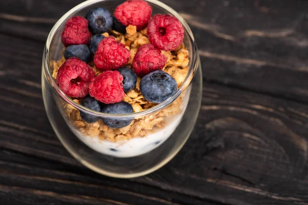 Leckeres Müsli mit Beeren und Joghurt im Glasbecher auf Holzoberfläche — Stockfoto