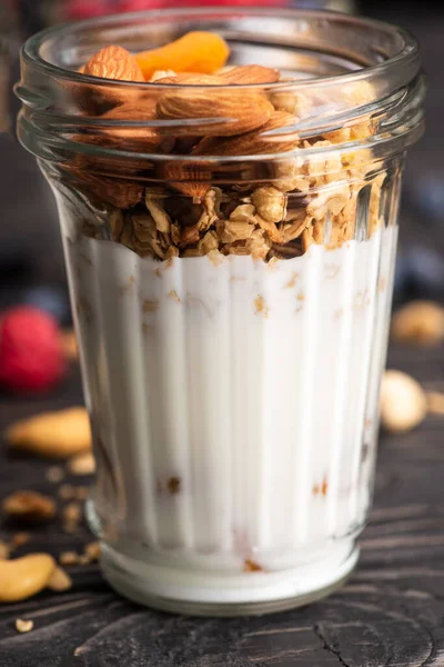 Close-up de granola deliciosa com damascos secos, nozes e iogurte em copo de vidro — Fotografia de Stock