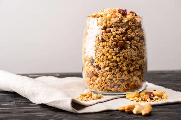 Delicious granola in glass gar on napkin isolated on grey — Stock Photo